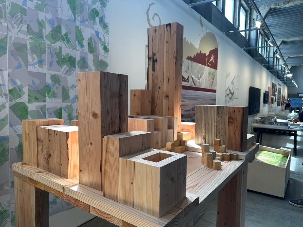 Timber site model in the exhibition hall, in front of the painted map wall